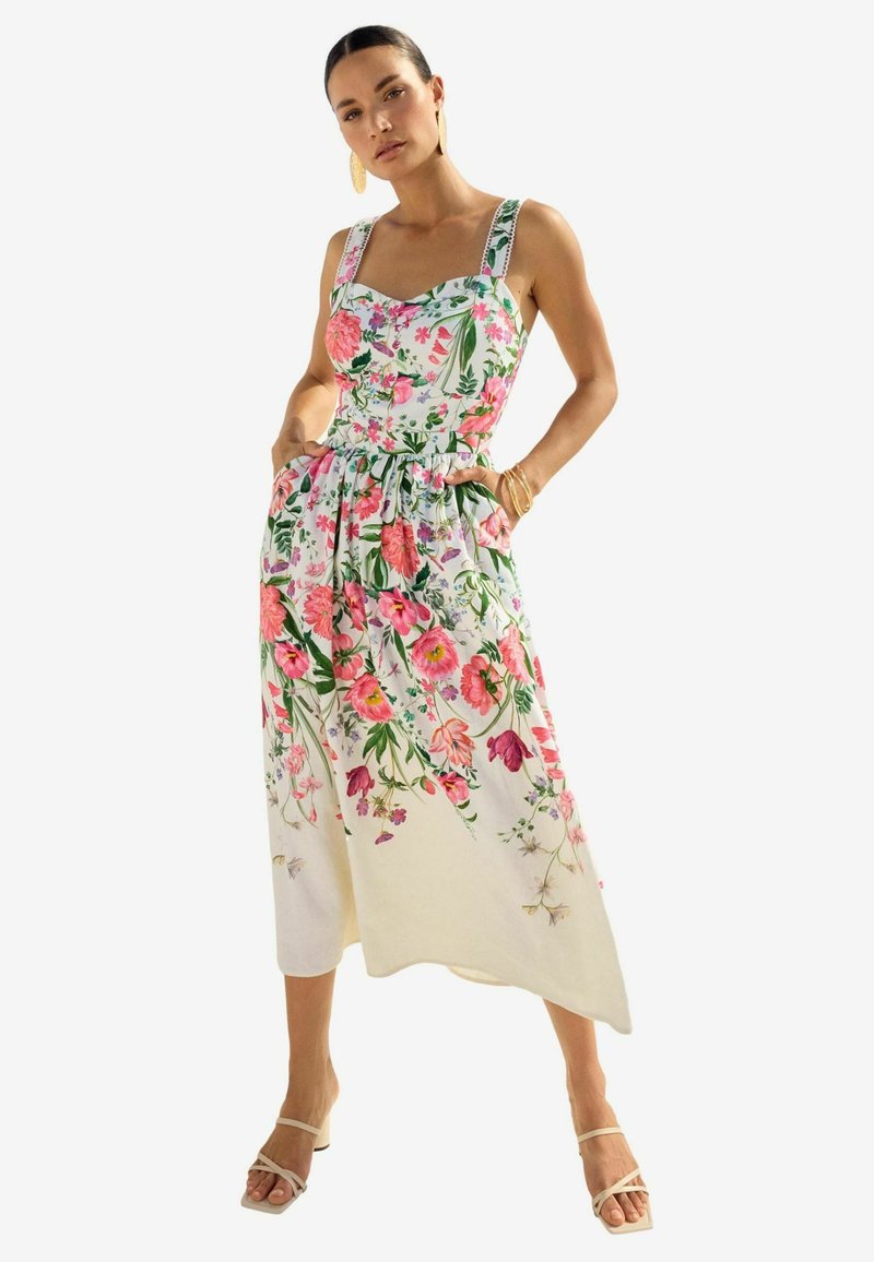 Floral midi haljina od laganog materijala s ružičastim, crvenim i zelenim botaničkim uzorcima. Ima usklađeni korzet, široke naramenice i bočne džepove.