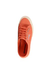Zapatillas de lona en color naranja con punta redonda, sistema de cordones y suela de goma beige. Presenta un parche con el logo en el costado y tejido texturizado.