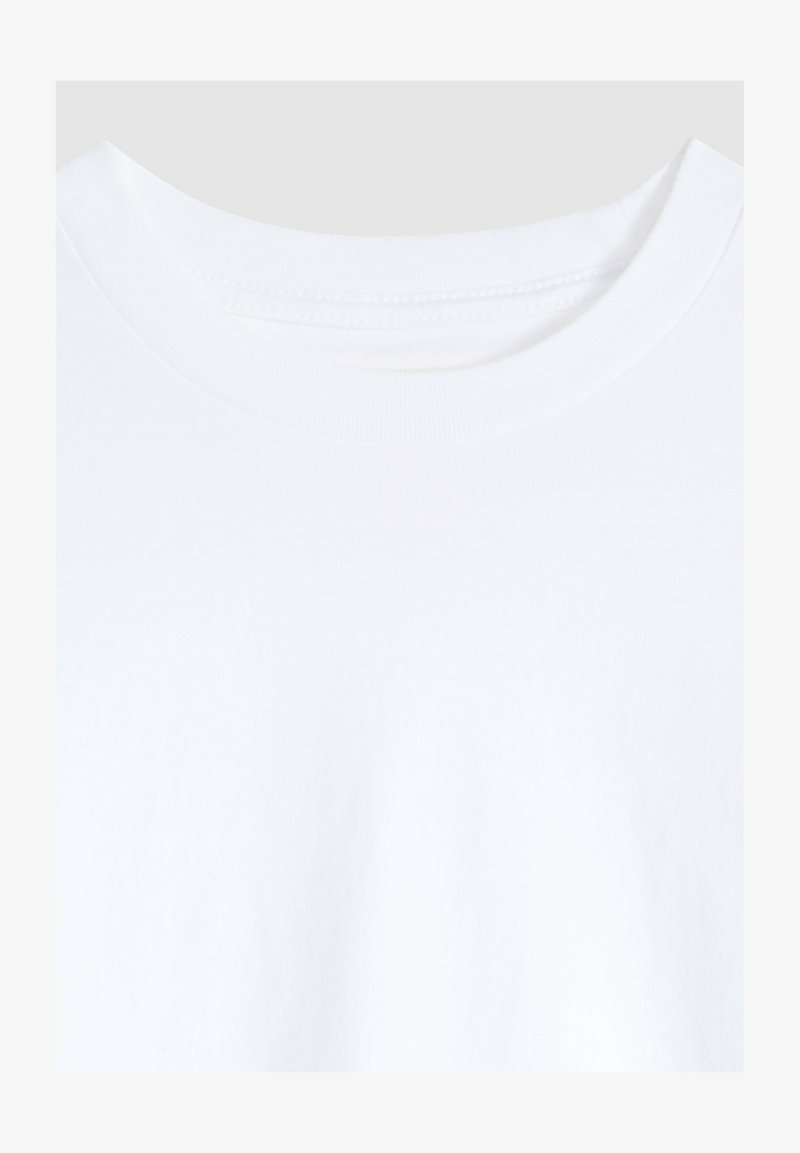 Hvid t-shirt med rund halsudskæring, der viser øverste bryst og rund hals med synlige syninger på ensfarvet baggrund.