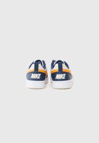 Baskets Nike bleues et oranges avec une finition en cuir lisse, dotées d'une semelle blanche et d'un marquage Nike bien visible sur le talon.