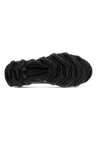 Black rubber shoe sole featuring deep treads and a textured surface, designed for traction and durability. Angular patterns throughout.