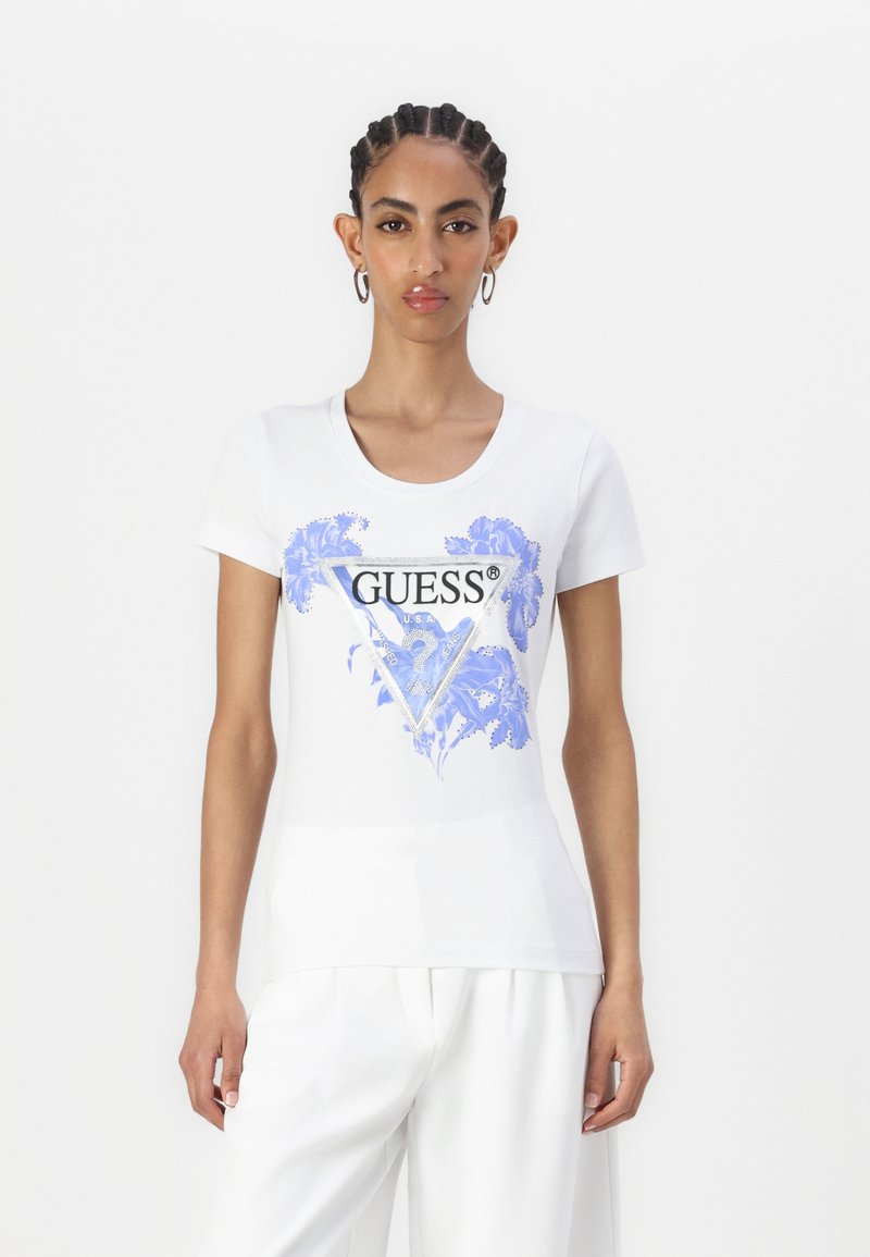 Bílé tričko s krátkým rukávem s modrou květinovou grafikou a logem „GUESS“ v trojúhelníkovém designu. Měkká, hladká textilie.