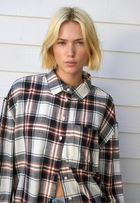 Geknoopte blouse in plaid met een mix van wit, marineblauw en roestkleur, met een relaxte pasvorm en een enkele borstzak.