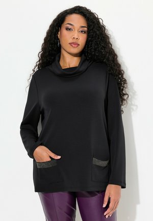 Haut noir à col cheminé en tissu doux, doté de manches longues, de deux poches avant avec des accents métalliques et d'une coupe décontractée.