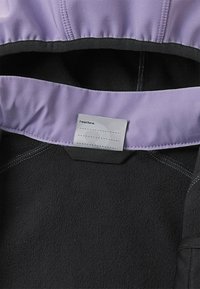 Haut en molleton noir avec une doublure lilas et une étiquette indiquant "J'étais ici." Présente des coutures contrastantes le long des coutures.