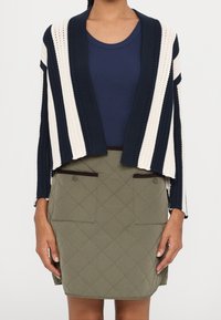 Proužkovaný pletený cardigan v námořnické modři a krémové barvě, doplněný o prošívanou olivově zelenou sukni s velkými předními kapsami a hnědými detaily.