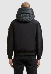 Schwarze Steppjacke mit großer, gesteppter Kapuze, Rippbündchen an Ärmeln und Saum. Glatter Stoff mit matter Oberfläche, ohne sichtbare Logos oder Muster.