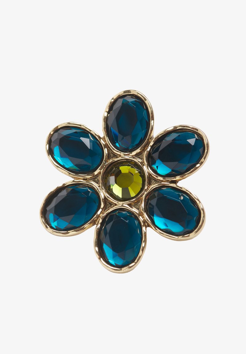 Spilla a forma di fiore in oro con sei grandi gemme ovali blu che fungono da petali e una gemma rotonda gialla al centro.