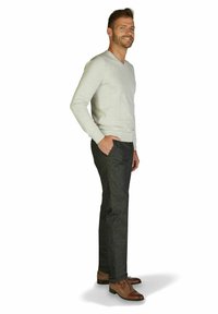 Grauer V-Ausschnitt-Pullover, dunkelgraue Hose mit subtiler Textur und braunen Lederschuhen. Das Model steht seitlich mit einer Hand in der Tasche.
