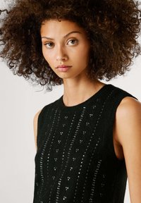 Μαύρο αμάνικο τοπ με υφή από σχέδιο και διακοσμητικές παγιέτες κατανεμημένες σε όλο το ύφασμα, με στρογγυλή λαιμόκοψη και εφαρμοστή γραμμή.