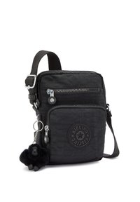 Black crossbody bag in ripstop nylon with a textured surface, one front pocket, and a furry gorilla charm attached. Adjustable strap.
