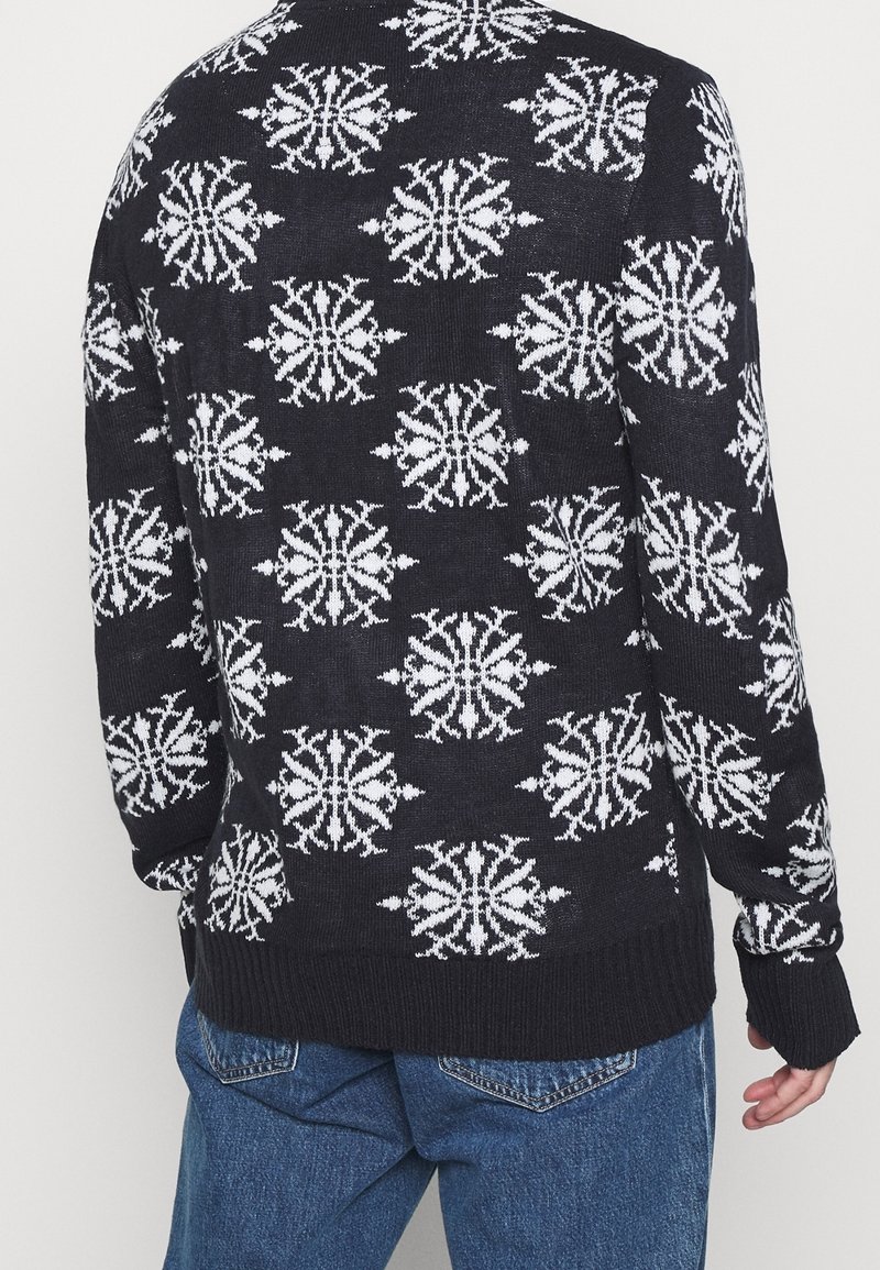 Pull en maille bleu marine avec motif flocon de neige blanc. Poignets et ourlet côtelés. Coupe standard, tissu légèrement texturé. Design classique à col rond.