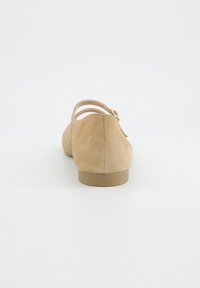 Chaussures en daim couleur fauve avec un bout légèrement arrondi, deux brides ajustables et un talon beige bas et solide. Texture lisse avec un design minimaliste.