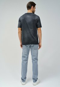 Camiseta de algodón gris oscuro con mangas cortas, combinada con jeans de mezclilla azul claro y zapatillas blancas; diseño liso sin patrones ni logotipos visibles.