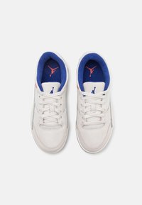 Sneaker in suede bianco con accenti blu e rossi, dotate di lacci piatti, colletto imbottito e un logo sulla linguetta e sulla soletta.