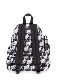 Mochila en blanco y negro con un patrón de caras sonrientes, con correas negras y un bolsillo lateral para una botella de agua. Se ve un compartimento con cremallera.