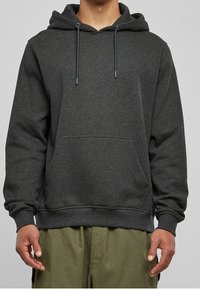 Tummanharmaa huppari, valmistettu pehmeästä kankaasta, jossa kengurutasku, säädettävät kiristysnauhat sekä resorit hihansuissa ja helmassa.