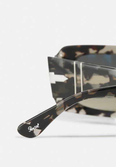 Ochelari de soare Persol cu un model de scoici negre și maro, având un design elegant, lentile verzi și un logo argintiu pe braț.