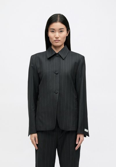 Zwarte blazer met krijtstreep, brede kraag, twee knopen en lange mouwen. Glad materiaal met een getailleerde pasvorm en zijzakken.