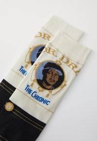 Knee-high socks in cream and black featuring a graphic of a person in a blue circle with "DR. D.R." and "THE CHRONIC" text above and below.
