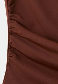 Gros plan d'un tissu marron avec une texture froncée le long d'un bord latéral.