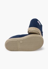 Marine canvas espadrille met een beige touw-midsol en een gestructureerde rubberen buitenzool. Heeft een kleurrijk label aan de zijkant.