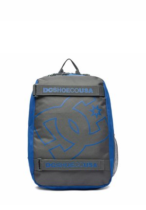 Grå og blå rygsæk med stort DC-logo og teksten "DCSHOECOUSA" på frontstropperne, to lynlåslommer og en netlomme på siden.
