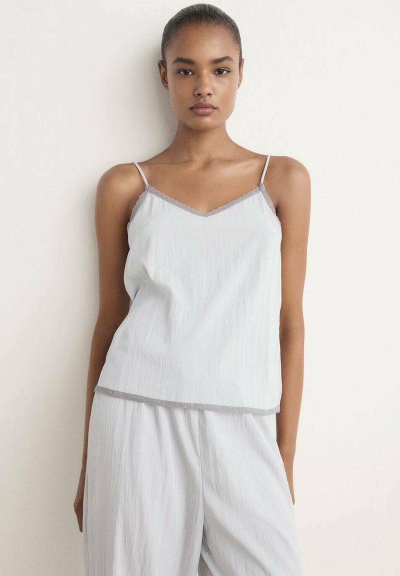 Camisole grigio chiaro con spalline sottili, caratterizzata da un collo a V e un delicato bordo grigio. Realizzata in un morbido tessuto testurizzato.