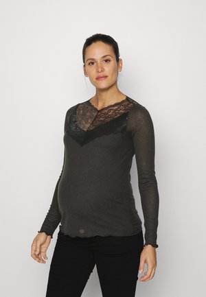 Blusa de gravidez de mangas longas, tecido cinza escuro com detalhes em renda preta na gola, forma ajustada, punhos com franzido e bainha arredondada.