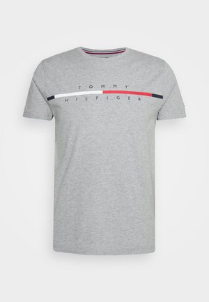 Hellgraues T-Shirt mit kurzen Ärmeln, das einen horizontalen roten, weißen und marineblauen Streifen mit „Tommy Hilfiger“-Text ober- und unterhalb des Streifens zeigt.
