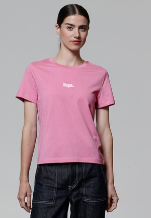 T-shirt en coton rose avec un col rond et des manches courtes. Présente un texte blanc "Nope." imprimé sur la poitrine. Design simple et classique.