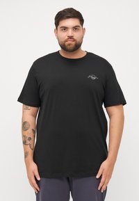 Zwarte katoenen t-shirt met een ronde halslijn, korte mouwen en een klein wit logo op de borst. Zachte textuur, ontspannen pasvorm.