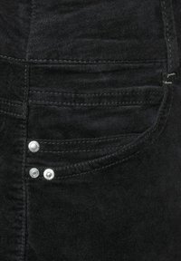 Sort denimstof med en baglomme, der har to sølvfarvede metalnitter og kontrastsyesyning. Glat tekstur med en ensartet farve.
