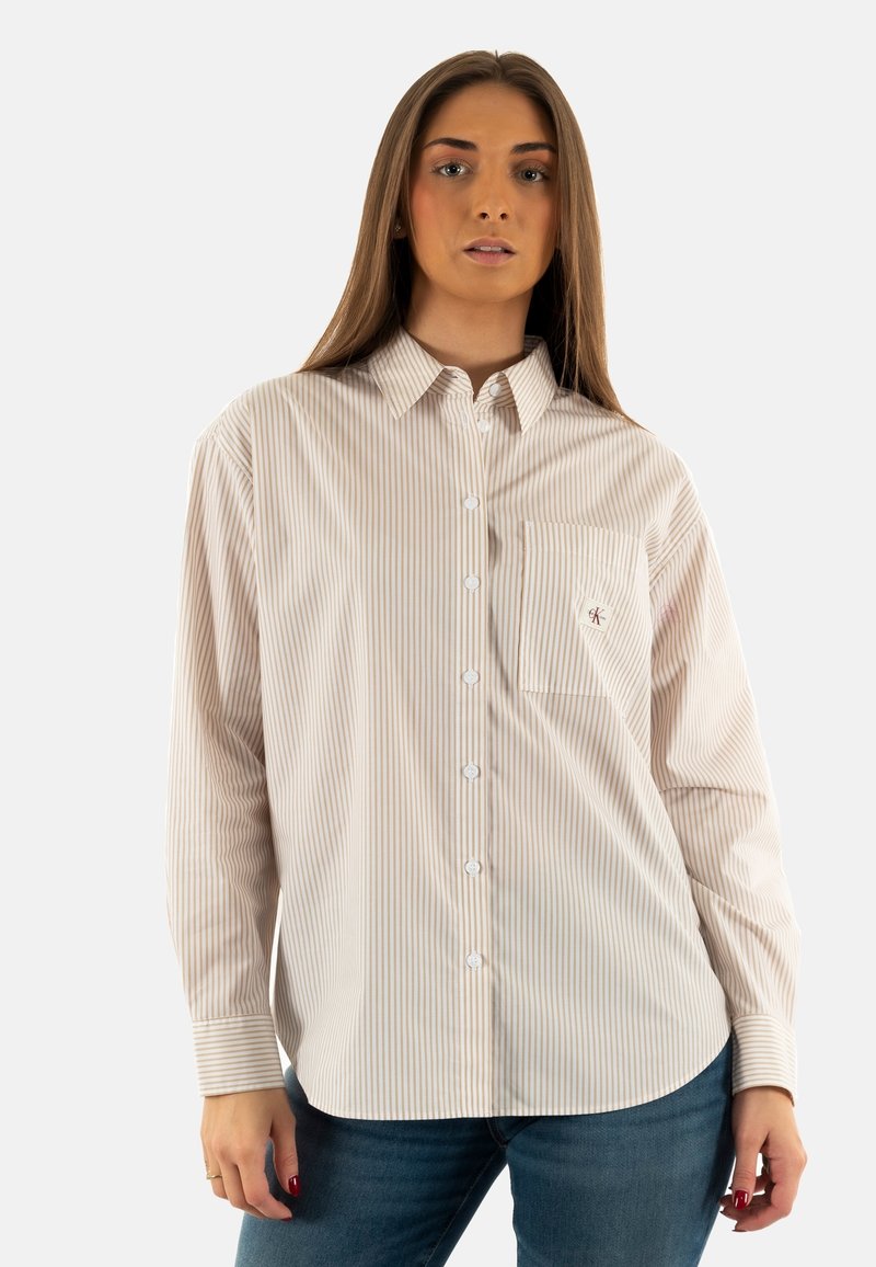Camisa de botones a rayas en beige y blanco, con un bolsillo en el pecho, cuello con puntas y mangas largas con puños abotonados.