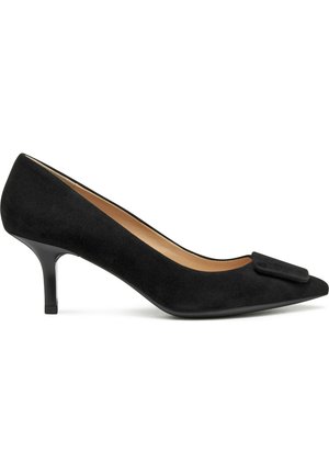 Chaussure à talon haut en daim noir avec un bout pointu et un petit nœud décoratif à l'avant. Dispose d'un talon fin et élégant et d'une doublure intérieure lisse.