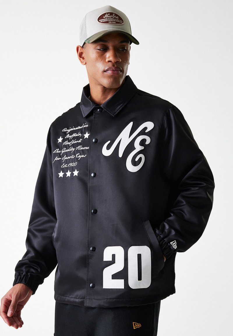 Black satin jacket featuring white "NE" logo, embroidered text, and the number "20" on the lower side. Includes snap-button closure and pockets.