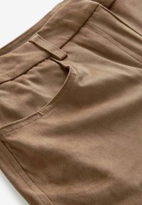 Tissu en daim marron avec une texture lisse, comportant une passante de ceinture et une poche frontale, avec des détails de couture le long des bords.