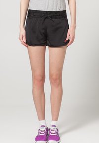 Svarta sportshorts med en strukturerad design, elastisk midja och snörningsdetalj. Matchade med lila sneakers och vita ankelsockor.