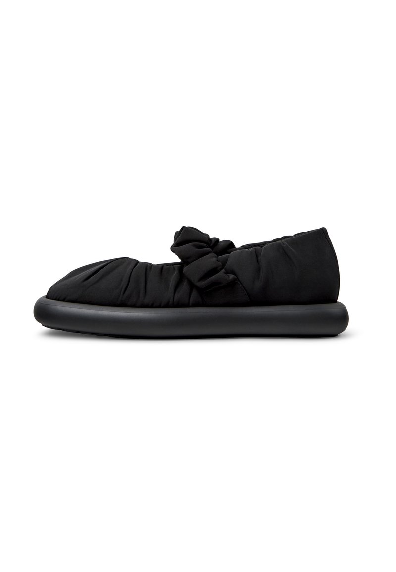 Scarpa nera slip-on con tomaia in tessuto morbido e arricciato, dettagli decorativi a fiocco, dotata di una suola in gomma liscia e arrotondata.