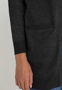 Dark gray cardigan made from a soft, textured knit fabric featuring long sleeves and two front pockets with ribbed cuffs.