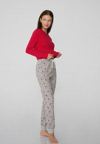 Rode longsleeve top gecombineerd met grijze pyjamabroek met een hondprint in feestelijke hoedjes, elastische tailleband en trekkoorddetail.