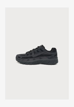 Chaussure de course Nike noire avec tige en mesh superposé et daim, semelle détaillée, et logo Nike visible sur le côté.
