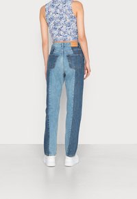 Ljusblå denimjeans med en lapptäckedesign, som har tvåfärgade paneler och dubbla bakfickor, i kombination med en blommig crop-top.