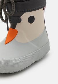 Botte de pluie en caoutchouc pour enfants avec un design gris clair et beige avec des accents orange et des détails circulaires noirs. Semelle texturée.