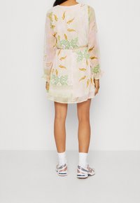 Lekka, wzorzysta sukienka z długimi rękawami, z wcięciem w talii, w delikatnych różowych i zielonych odcieniach. Noszona z trampkami i krótkimi skarpetkami.