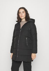 Abrigo de plumas negro con capucha, que cuenta con bolsillos frontales con cremallera, un cierre frontal con cremallera y una textura acolchada para aislamiento.