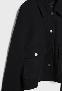 Černý vlněný kabát s límcem, předními patentkami a dvěma kapsami s klopami se stříbrnými patentkami.