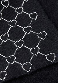 Black fabric featuring a pattern of outlined hearts created with small, silver beads arranged in a grid-like design.