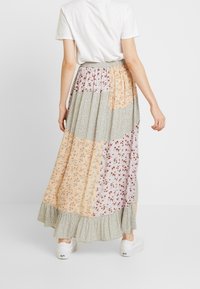 Jupe longue avec un design patchwork aux motifs floraux dans des couleurs pastel, un ourlet à volants et une taille élastique.