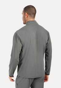 Grå fleecejakke med høj krave, lange ærmer og en glat tekstur. Har sort kant ved manchetten og et slankt design.